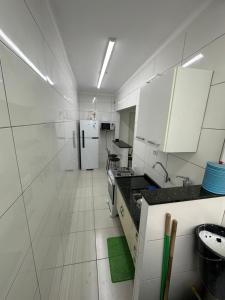 a kitchen with white cabinets and a green rug at Kitnet em frente a praia de Santos in Santos