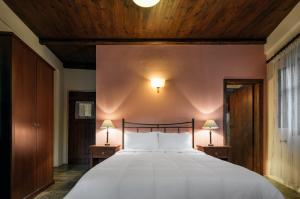 a bedroom with a large white bed with a wooden ceiling at Porto Kale Guesthouse in Porto Kagio