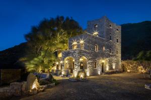 a large stone building with lights on it at night at Porto Kale Guesthouse in Porto Kagio