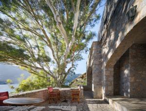a patio with chairs and a table and a tree at Porto Kale Guesthouse in Porto Kagio