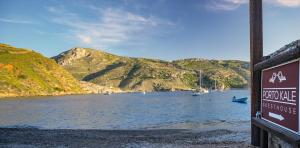 a sign on the shore of a body of water with boats at Porto Kale Guesthouse in Porto Kagio
