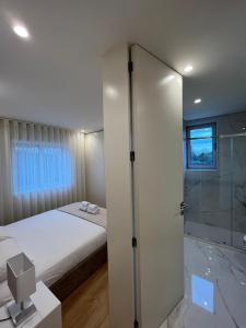 法馬利康新鎮的住宿－Brittos Home Lovely Stay - Villa Prime in VN de Famalicão Braga，一间卧室设有一张床和一个玻璃淋浴间