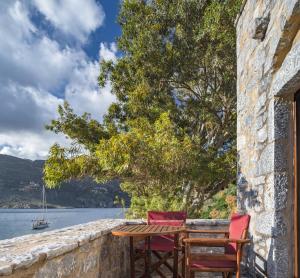 a table and chairs on a stone wall with a view of the water at Porto Kale Guesthouse in Porto Kagio