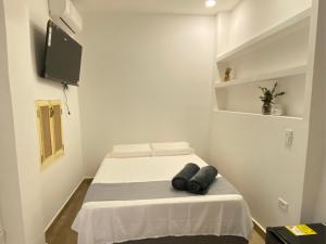 a small white room with a bed and a tv at Casa Zaguan in Cartagena de Indias