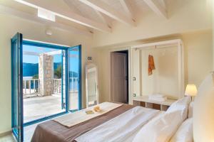 a bedroom with a large bed and a balcony at Heliopetra Luxury Villa Lefkas in Vasiliki
