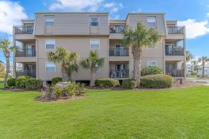 an apartment building with palm trees in front of a yard at Salty Dogs - Gated, Private Dock, Beach Access in Myrtle Beach
