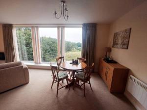 sala de estar con mesa, sillas y ventana en Otterhole Barn Holiday Apartment, en Buxton