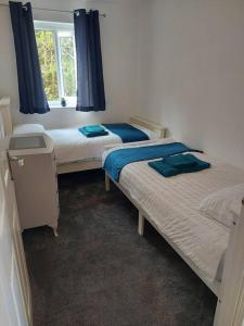 two twin beds in a room with a window at Otterhole Barn Holiday Apartment in Buxton