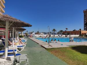 a pool with chairs and people in the water at Hotel PYR, Spacious Studio with a Big Terrace in Fuengirola
