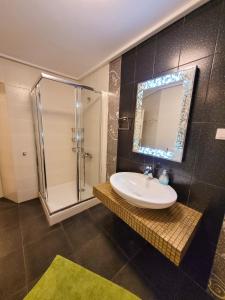 a bathroom with a sink and a shower with a mirror at Centaur Villa in Agios Ioannis Pelio