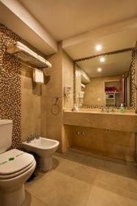 a bathroom with a toilet and a sink and a mirror at Hotel Intersur La Cumbre in La Cumbre