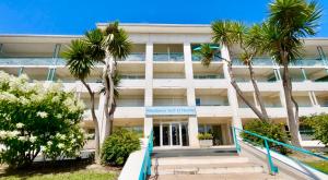 an office building with palm trees in front of it at Caprozion-Erosoa-T1-Piscine-Clim in Ciboure