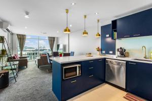 een keuken met blauwe kasten en een woonkamer bij Urban Horizon with sea views and pool in Auckland