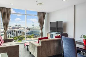 een woonkamer met een bank en een tv bij Urban Horizon with sea views and pool in Auckland
