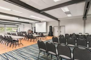 a conference room with tables and chairs and a screen at Columbia River Hotel, Ascend Hotel Collection in The Dalles in The Dalles