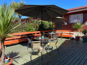 a patio with a table and chairs and an umbrella at Hotel Cabañas Caribe in Los Vilos +25 photos