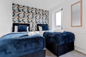 a bedroom with two beds with blue covers and a window at Luxury Birmingham City Centre Townhouse with FREE Parking - Sleeps 4 - Perfect for Contractors, Business Travellers, Families and other Groups - Near Bullring, Newstreet, Selfridges, NEC, NIA & Birmingham airport in Birmingham