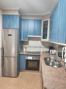 La cuisine est équipée de placards bleus et d'un réfrigérateur en acier inoxydable. dans l'établissement Casa Carla, à Sotoserrano