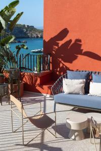 a couch and chairs on a patio with a view of the water at La Roqqa in Porto Ercole