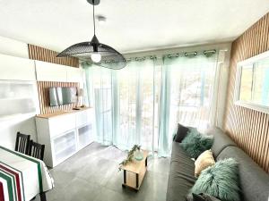 a living room with a couch and a large window at Caprozion-Erosoa-T1-Piscine-Clim in Ciboure