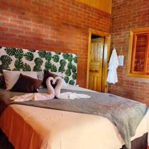 a bedroom with a bed with two swans on it at Chalé Jequitiba, hidro, lareira, natureza, Sul de Minas in Sapucaí-Mirim