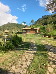 une maison au sommet d'une colline avec un chemin en pierre dans l'établissement Chalé Jequitibá- Valedaspedrasmg, à Sapucaí-Mirim