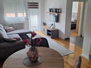 een woonkamer met een vaas met bloemen op een tafel bij Apartman Pepper in Osijek