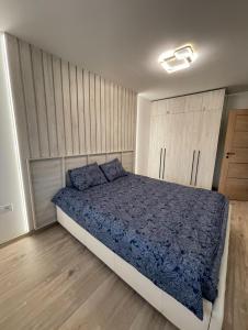 ヴェンツピルスにあるCozy Retreat Apartmentのベッドルーム1室(青いシーツとウッドフロアのベッド1台付)