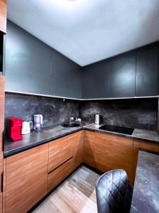 une cuisine avec des placards en bois et un comptoir noir dans l'établissement Cozy Retreat Apartment, à Ventspils
