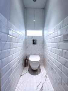 a white bathroom with a toilet and a window at Cozy Retreat Apartment in Ventspils