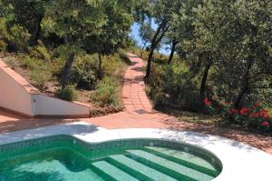 a swimming pool next to a brick path with trees and flowers at Finca La Fronda in Alájar