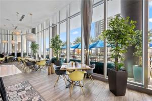 un restaurante con mesas, sillas y ventanas en High Floor Corner 2 BDR in Hyde Resort en Hollywood