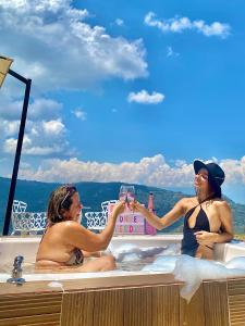 twee vrouwen zitten in een badkuip met een glas wijn bij Glamping Monteverde San gil in San Gil