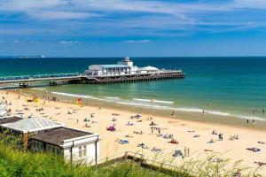 a group of people on a beach near a pier at Homely Apartment in the Heart of Town Centre - Sleeps 6 in Bournemouth