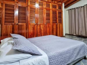 里奧內格羅的住宿－HOSTAL - Casa Rionegro -10 min del aeropuerto，一间卧室设有木墙和一张带枕头的床。