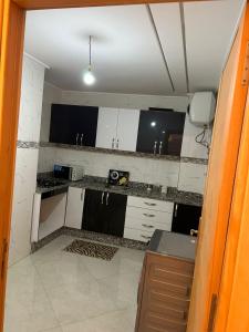 a kitchen with white cabinets and black and white tiles at le Lys apprt Oujda in Oujda