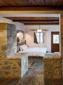 a bedroom with a bed and a stone wall at Porto Kale Guesthouse in Porto Kagio