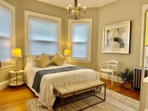 1 dormitorio con 1 cama con lámpara de araña y 2 ventanas en Large Elegant Home Walk to BROWN RISD, en Providence