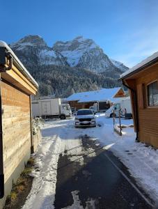 Chalet at Ski Lift (Gsteig b. Gstaad) في Gsteig: سيارة متوقفة في موقف مع جبل مغطى بالثلج