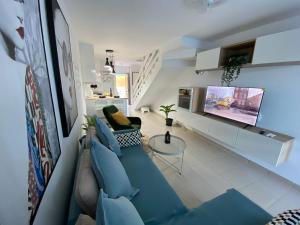 a living room with a blue couch and a tv at CarpeDiem Costa de Antigua in Costa de Antigua