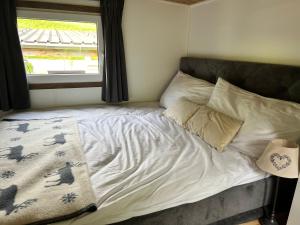 - un lit avec des draps et des oreillers blancs à côté d'une fenêtre dans l'établissement Chalet at Ski Lift (Gsteig b. Gstaad), à Gsteig