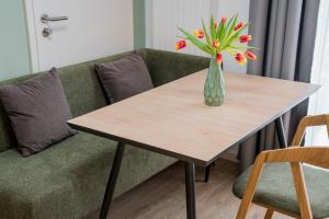 a table with a vase of flowers on a couch at Nena Apartments Berlin - Adlershof - "New Opening 2024" in Berlin