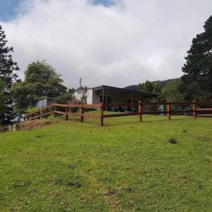 a wooden fence in a field with a house at Fairmont Cottage in Woodhill