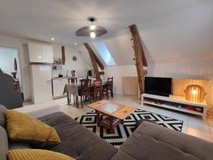 ein Wohnzimmer mit einem Sofa und einem Tisch in der Unterkunft Appartement au coeur de la Suisse normande in Thury-Harcourt
