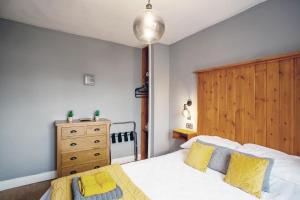 a bedroom with a bed with yellow pillows and a wooden headboard at Stylish 2-Bed Cottage in the heart of Yorkshire in Leeds