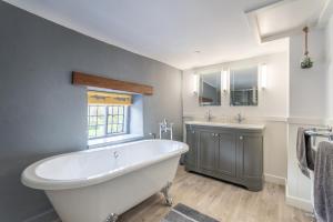 baño con bañera blanca grande y lavamanos en Luxury cosy cottage, enchanting forest location. en Ringwood