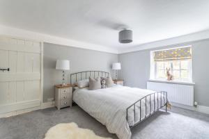 a white bedroom with a bed and a window at Luxury cosy cottage, enchanting forest location. in Ringwood