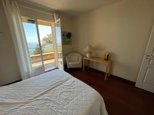 una camera da letto con un letto, un tavolo e una finestra di Maison En Pierre Corse Vue Mer a Sari Solenzara