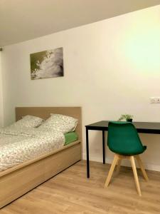 1 dormitorio con cama, escritorio y silla verde en Magnifique appartement pouvant accueillir 6 personnes à 20 minutes de paris, en Antony