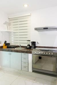 a kitchen with a counter with a stove and a sink at Casa Ohana By Utopia in Playa del Carmen